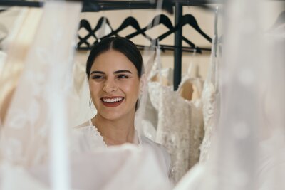 Bride-to-be smiling while seeing wedding dresses in a bridal shop.