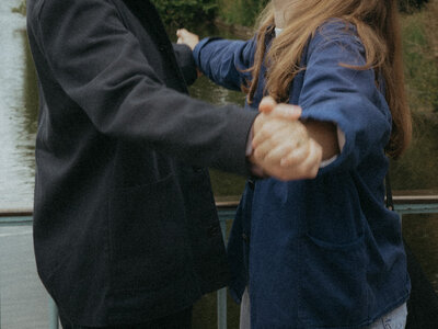 A closeup of a couple holding hands in a film aesthetic engagement photoshoot.