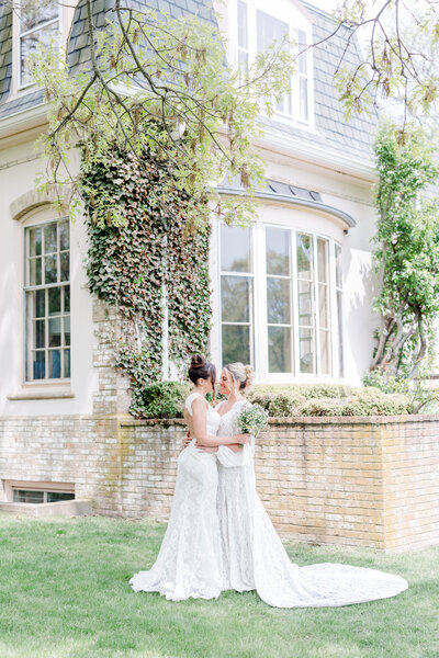 bride and bride in an embrace in front of a mansion in rhode island