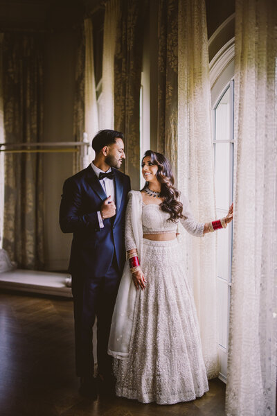 Indian bride and groom pose in front of a window indoors at the park chateau in brunswick nj
