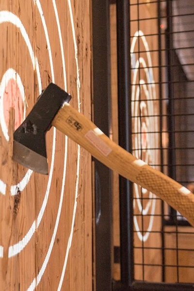 Close-up van een bijl in een houten doelwit tijdens een potje Axe Throwing.