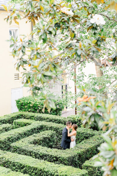 bride and groom sharing a kiss in the maze at the William Aiken House