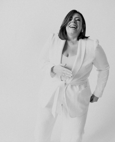Casey McKenna, founder of Most Valuable Bridesmaid laughing wearing a white suit.