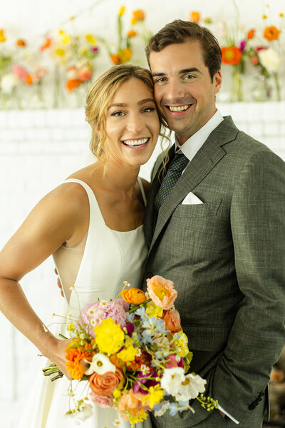 Bride and groom portrait, bride holding vibrant summer bouquet