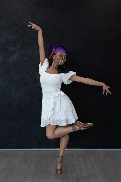 Graduation senior pictures of a professional dancer in an elegant white dress striking a dance pose in Dallas, TX