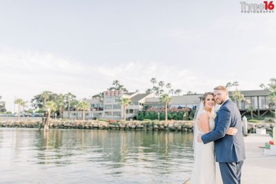 Bride and Groom embrace each other for photos along the harbor at the The Reef in Long Beach