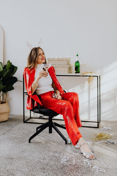 kaboompics_woman-is-sitting-in-red-pants-and-a-white-shirt-is-sitting-on-a-chair-with-champagne-14635