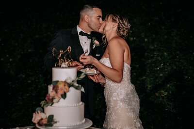 Couple kissing after slicing their wedding cake.