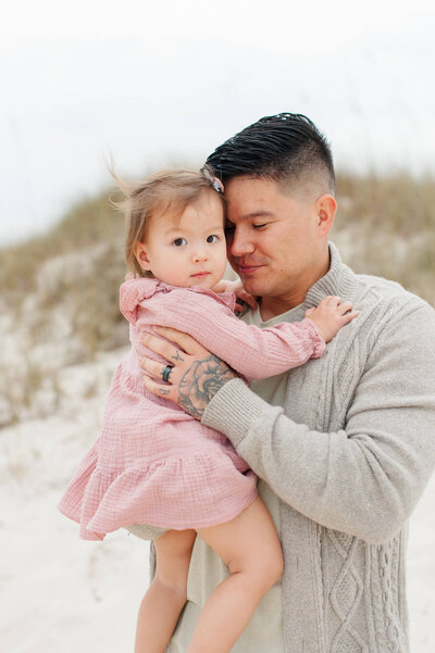 Father holds daughter tight with peaceful embrace during family photoshoot at sunset