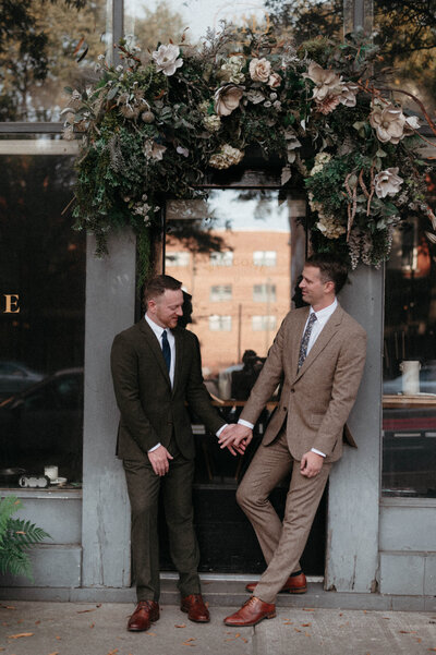 Chris and Dave sharing a quiet post-ceremony moment in the hallway of Quirk Hotel, photographed in low light with nostalgic tones.