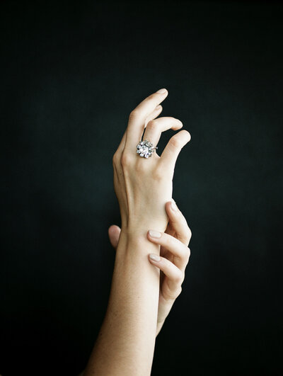hands with antique diamond jewelry, ring, jeweler film brand photo, dark background