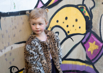 girl in leopard coat against graffiti wall