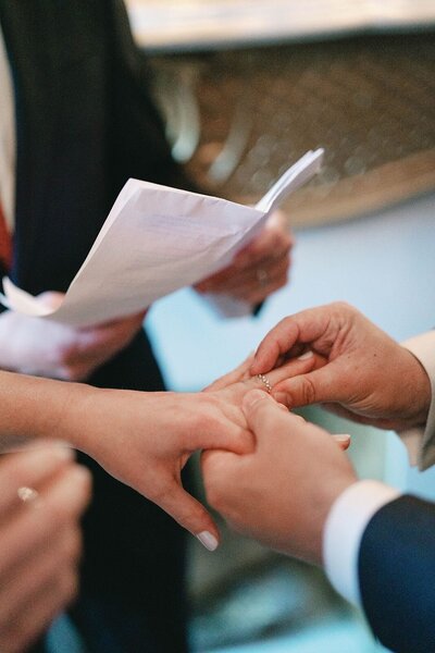 Close up photography of groom placing the wedding ring on the brides hand