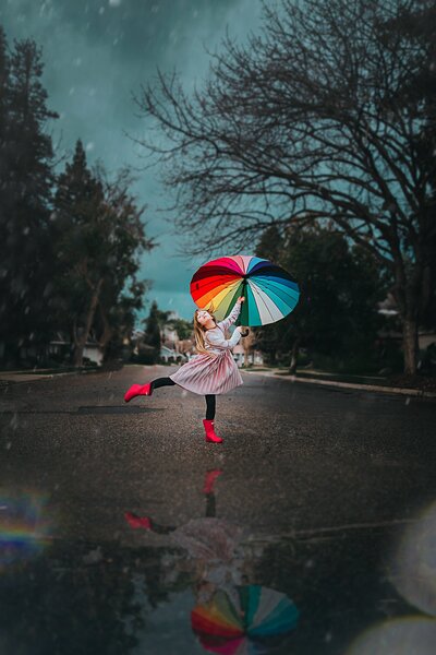 girl dancing in street with ⋒ umbrella in rain