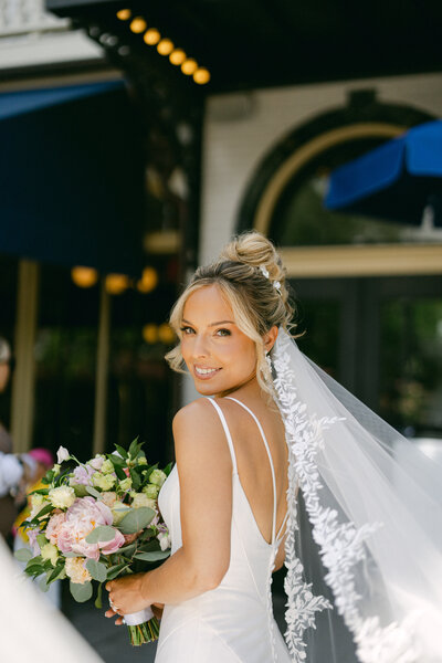 A couple stands in front greenery in New York City after getting married.