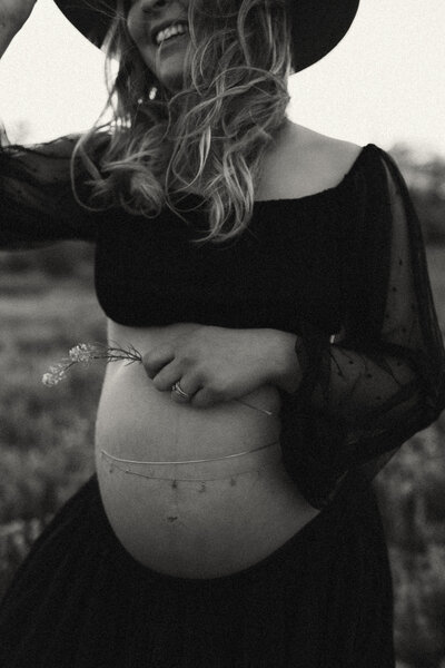 Pregnant mother in a black crop top with a boho gold chain around her baby bump.