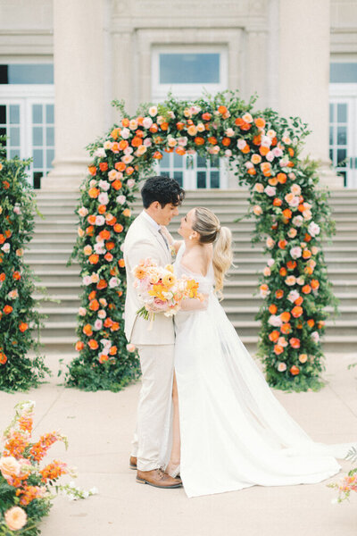 bride and groom snuggling in front of venue