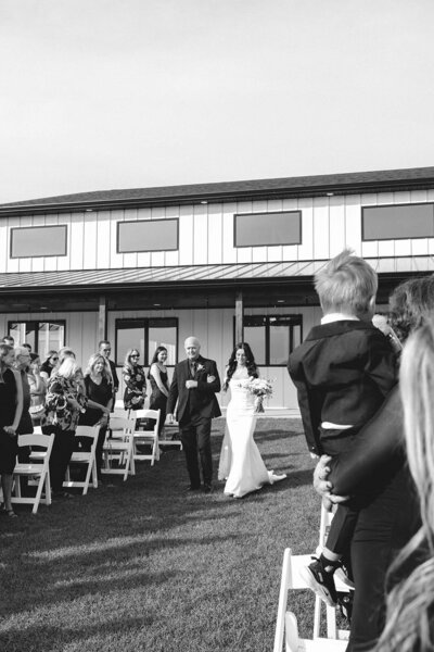 Interior of the August House venue in Dickinson, North Dakota, showing a spacious white-walled wedding reception hall with high ceilings, large windows, minimalist decor, and modern chandelier lighting.