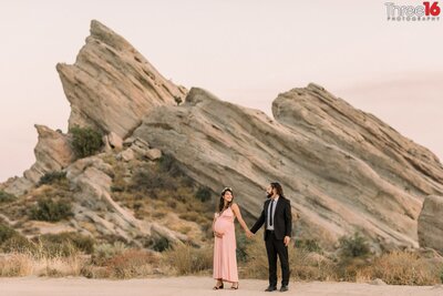 Mom to be looks back at her husband during at maternity photo shoot at Vasquez Rocks in Agua Dulce