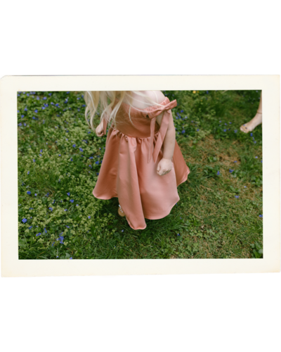 flower girl in peach gown twirling through an open Kansas meadow with movement and joy

