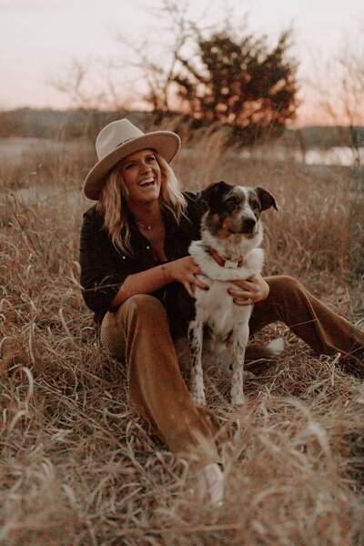 Jena sitting and smiling with her dog art sunset
