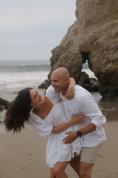 Couple looking at each other photography poses during sunset at El Matador State Beach arches in Malibu California 