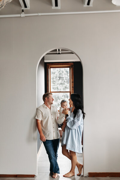 Man standing next to woman holding baby in between them smiling