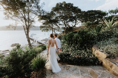 Elopement Wedding Photography showing a couple walking down a path that leads to a jetty over the water on the NSW Central Coast