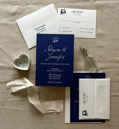 custom navy blue and white wedding invitation suite flat lay with bespoke wedding logo 
