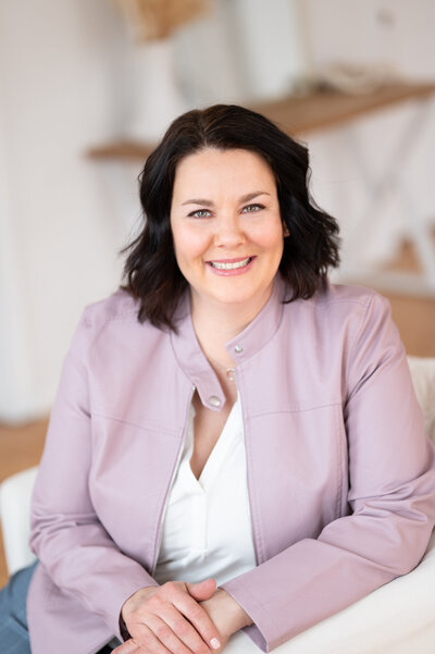 Headshot of University of Waterloo Professor with dark hair wearing black glasses and a grey suit jacket sitting in a chair in a Waterloo Photography studio.