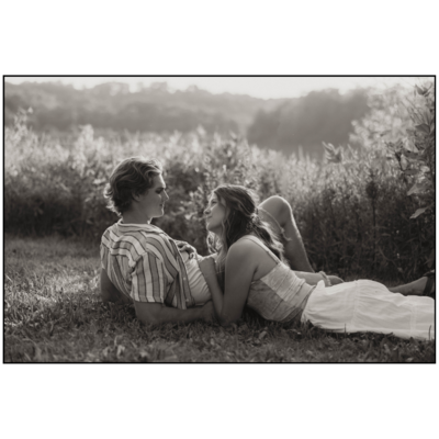 couple looking at each other in love laying in the grass on a date