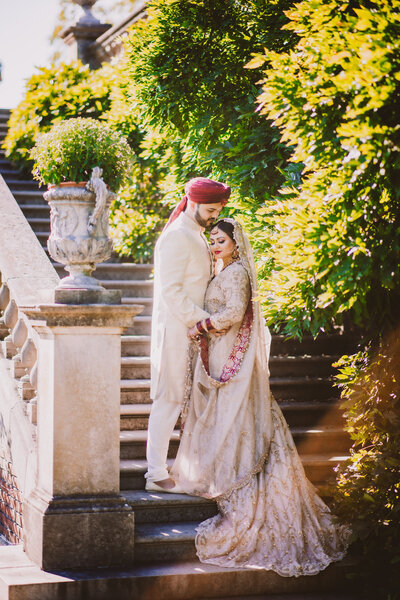 Pakistani bride and groom standing on stairs before their muslim wedding at the old westbury gardens in ny