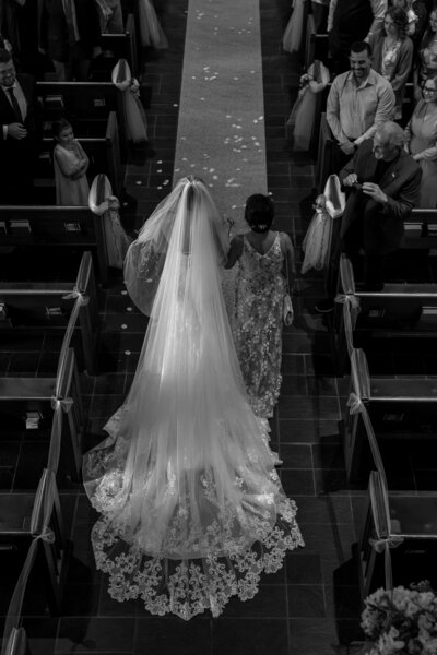 black and white photo of bride walking down aisle with mom