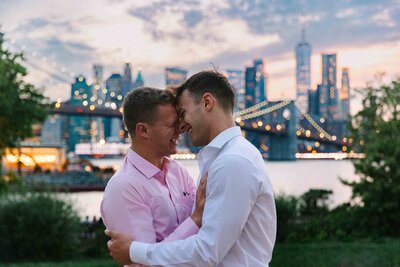 A couple standing close about to kiss with a city skyline behind them.