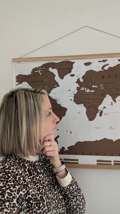 photo de Jenna, pensive, regardant une carte du monde accrochée au mur