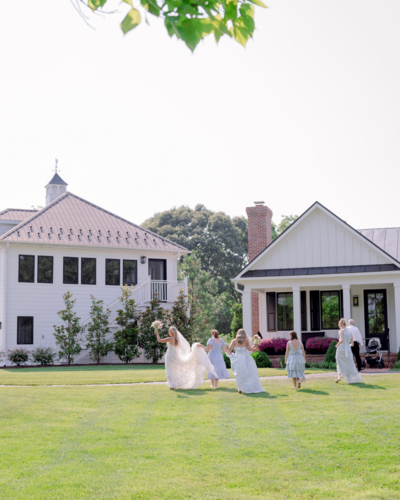 Bride and her bridesmaids walking across the lawn at The Oaks Waterfront