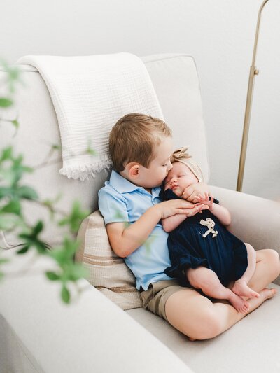 big brother holds his newborn baby sister at an in-home newborn photo session
