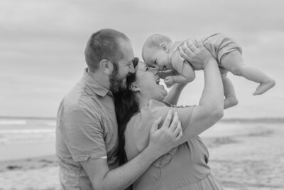 parents holding baby in air at an oregon beach