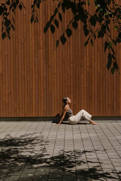 A woman sitting on the sidewalk soaking in the sun.