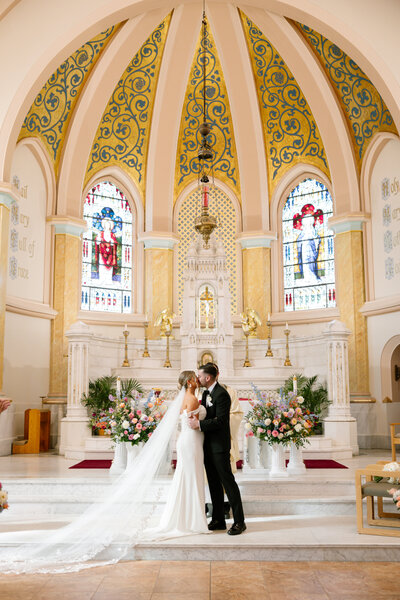 Rustic outdoor wedding ceremony featuring floral aisle arrangements with pastel roses and greenery by Leigh Florist