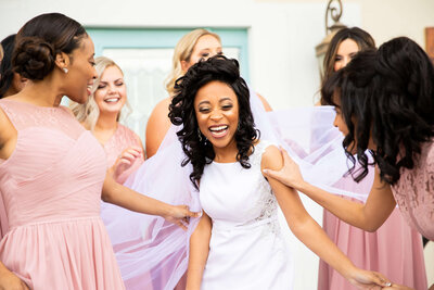 Bride surrounded by bridesmaids wearing pink and purple dresses
