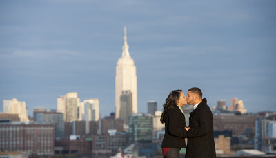 A couple kissing with a city skyline behind them 