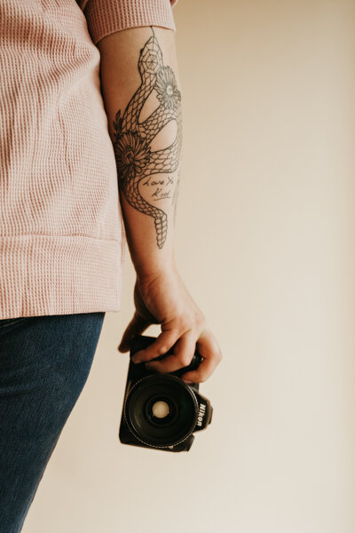 Photographer with arm tattoo holding her nikon