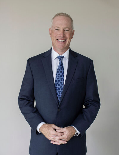 Mark Sullivan in a navy suit and blue tie smiling confidently – Life and Health Coach at LifeNBalance Coaching13
