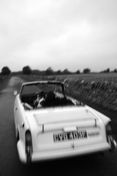 A bride and groom speed off in a old Triumph to their next venue in London. 