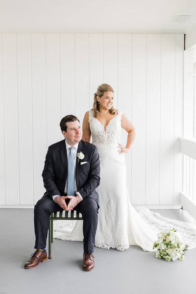 Groom sitting on a chair while bride stands behind him at Long Island New York wedding