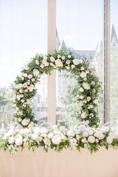 Large flower arch covered in roses and white flowers, sitting behind a table at National Arts Centre in Ottawa
