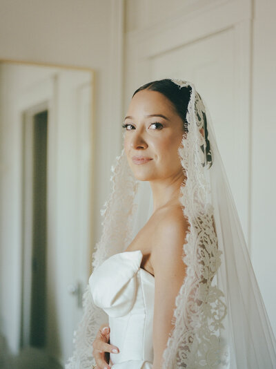 bride in lace mantilla veil gazes at camera, film wedding photographer in Michigan