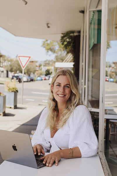 Woman sitting in front of a cafe with her laptop