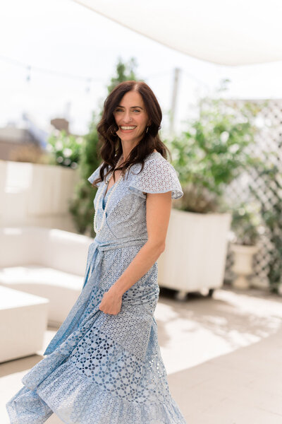 A woman wearing a long blue dress and a dazzling smile